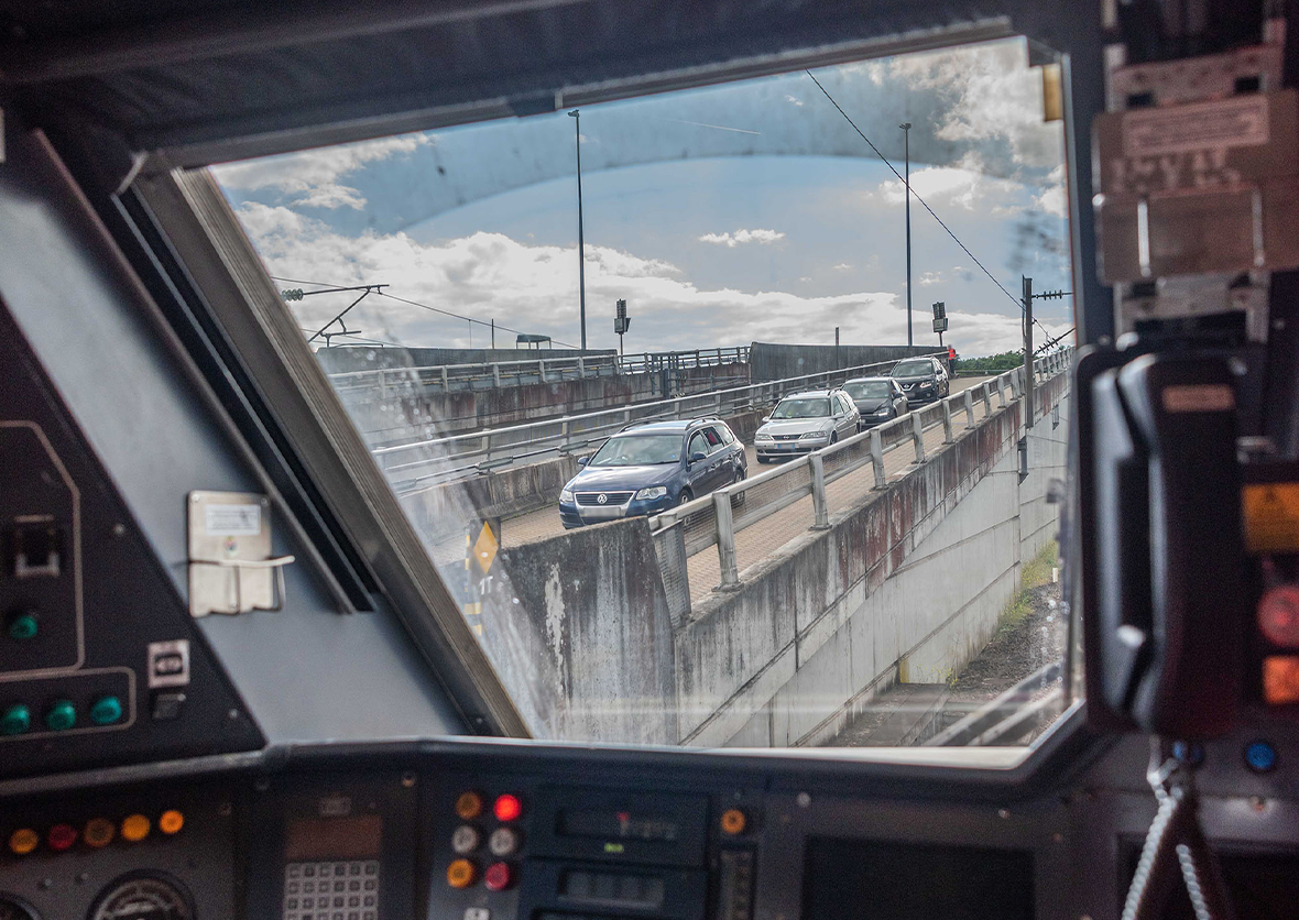View from a driver’s window of four cars driving down a concrete ramp towards the shuttle
